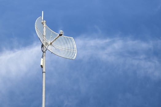 Internet wireless wifi receiver and repeater installed on metal pole on the roof of the building to service internet to users in local village, soft and selective focus. photo
