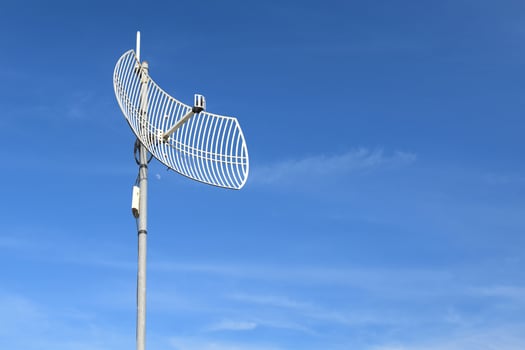 Internet wireless wifi receiver and repeater installed on metal pole on the roof of the building to service internet to users in local village, soft and selective focus. photo