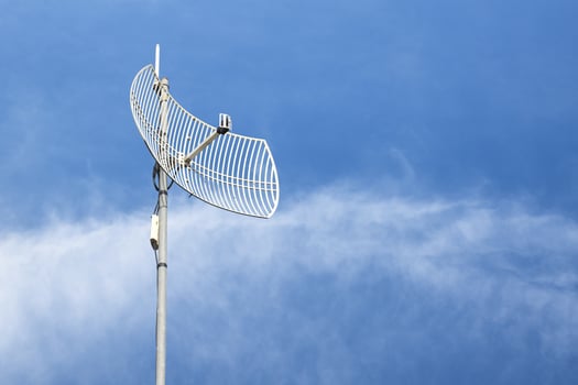 Internet wireless wifi receiver and repeater installed on metal pole on the roof of the building to service internet to users in local village, soft and selective focus. photo