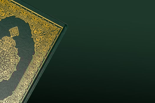 The Holy Al Quran with written arabic calligraphy meaning of Al Quran and rosary beads or tasbih on dark green black background with copy space. photo