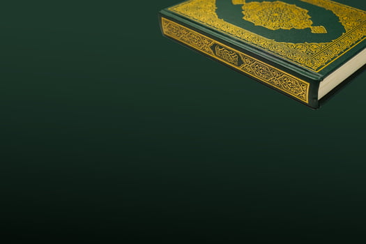 The Holy Al Quran with written arabic calligraphy meaning of Al Quran and rosary beads or tasbih on dark green black background with copy space. photo