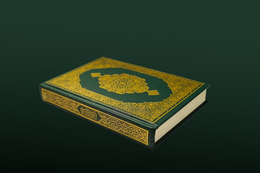 The Holy Al Quran with written arabic calligraphy meaning of Al Quran and rosary beads or tasbih on dark green black background with copy space. photo