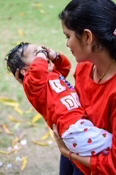 Loving mom carrying of her baby at society park. Bright portrait of happy mum holding child in her hands. Mother hugging her little 9 months old son. photo