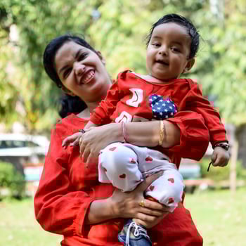 Loving mom carrying of her baby at society park. Bright portrait of happy mum holding child in her hands. Mother hugging her little 9 months old son. photo