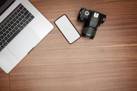A laptop and a camera on a wooden table photo