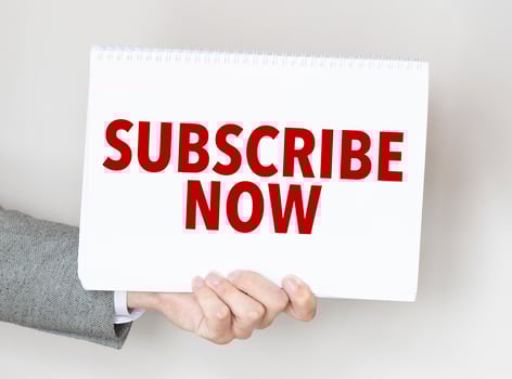man's hand holding paper sheet with subscribe now words photo