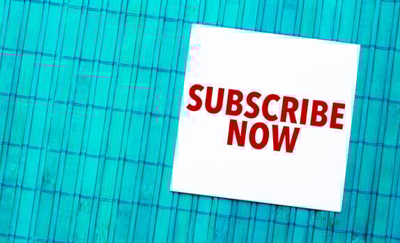 subscribe now word on torn paper with blue wooden background photo