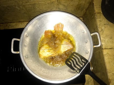 fish that is being fried using oil in a cooking pot photo