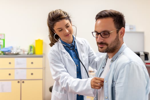 Caring Caucasian female doctor use phonendoscope examine male patient heart rate at consultation in hospital. Woman nurse or GP use stethoscope listen to man heartbeat in clinic. photo