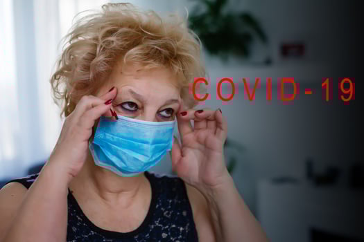 Portrait of coughing elderly woman wearing protective mask on grey background photo