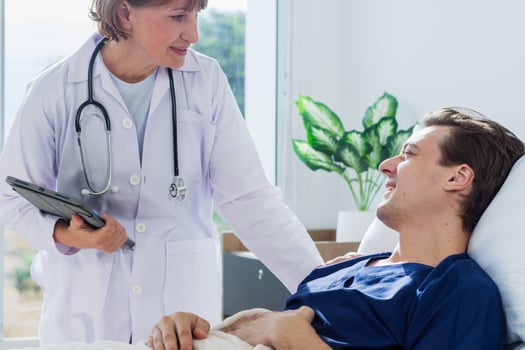 the doctor is examining the patient in the hospital. Caucasian female doctor talking to male patient lying in hospital bed. photo