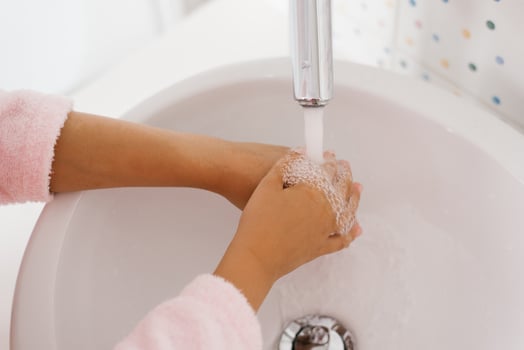 Close up view of young child washing hands with soap in sink photo