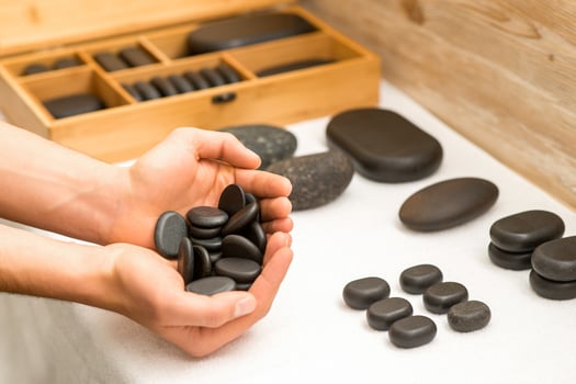 Hands holding spa black pebbles photo