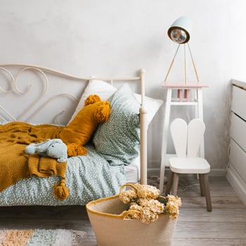 Stylish children's room of the child. Wicker basket with flowers, pillows on the bed mint and brown photo