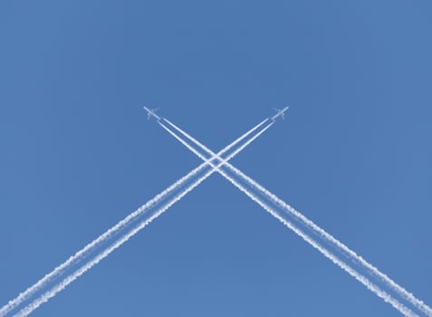 crossing of two aircraft traces in a blue sky photo