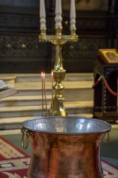Christening in the church. Church utensils in the Orthodox church. A big bowl of water for the baptism of a baby with wax candles. photo
