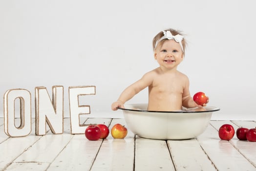 Beautiful baby bathes in a basin. One year old baby on his first birthday. photo