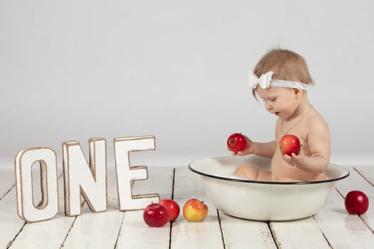 Beautiful one-year-old girl bathes in a basin. Photoshoot on your first birthday. photo