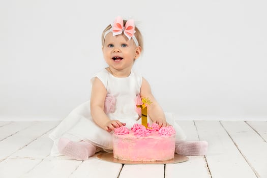 Cheerful little girl with a festive cake. Beautiful girl one year old. photo