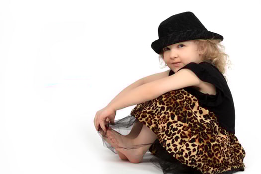 Beautiful child. Little blonde girl in a black hat on a white background. A four year old child is sitting. Model child. photo