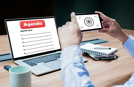 Businessman using smart phone to take picture of laptop with agenda topic on display photo