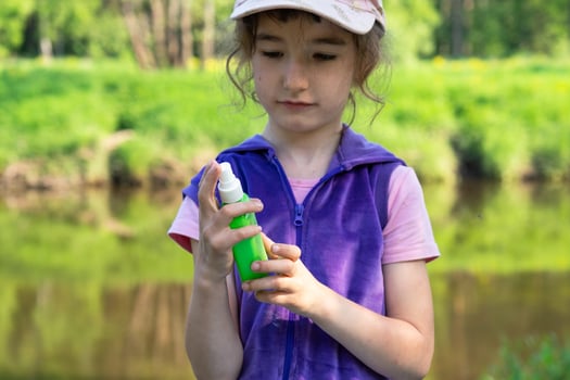 Girl sprays mosquito spray on the skin in nature that bite her hands and feet. Protection from insect bites, repellent safe for children. Outdoor recreation, against allergies. Summer time photo