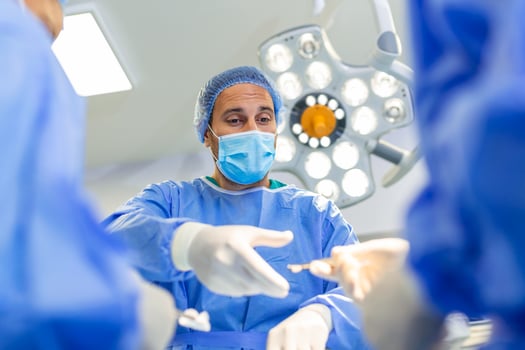 Low Angle Shot in the Operating Room, Assistant Hands out Instruments to Surgeons During Operation. Surgeons Perform Operation. Professional Medical Doctors Performing Surgery. photo