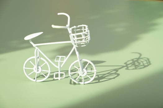 Decorative white bycicle on green background with hard shadows. Sustainable lifestyle concept photo