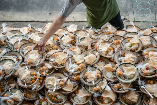a man prepares takjil food at the jogokariyan mosquea man preparing takjil food at the jogokariyan mosque, so many stacks of plates filled. photo