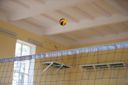 A volleyball ball flies over the net. Volleyball in the gym. photo