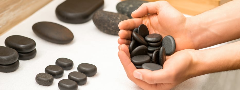 Hands holding spa black pebbles photo