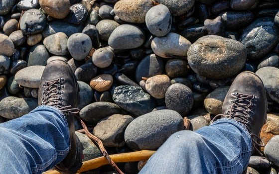 Close up of man's legs wearing jeans and boots at a rocky beach photo