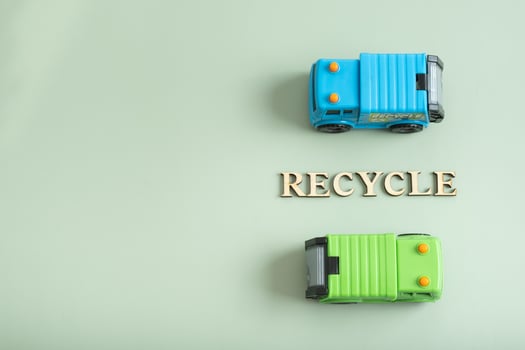 Toy garbage trucks and recycle text on a green background. Recycling concept photo