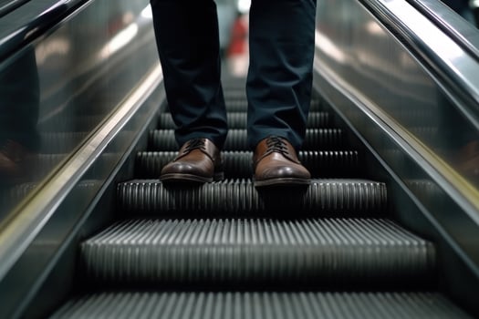 businessman legs in a suit and shoes down steir the escalator shopping center photo