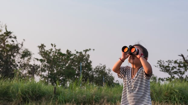 Cute girl looking through binoculars, concept of hiking, camping and adventure. photo
