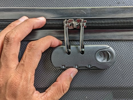 man hands unlocking a code padlock on a suitcase photo