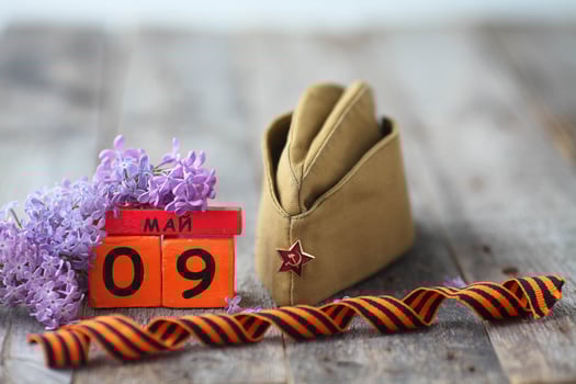 Wooden calendar with Russian text May 9, garrison cap, george ribbon and a bouquet of lilacs on a wooden background. Victory Day. photo