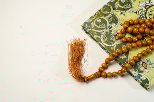 The Holy Al Quran with written arabic calligraphy meaning of Al Quran and rosary beads or tasbih on white background with copy space. photo