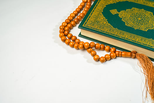 The Holy Al Quran with written arabic calligraphy meaning of Al Quran and rosary beads or tasbih on white background with copy space. photo