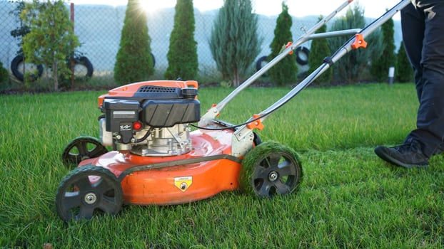 Lawn mowing. Man cutting grass with his orange lawn mower. photo