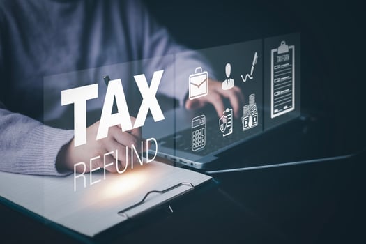 Businessman using a pen to write a notebook with TAX REFUND and refund tax of duty taxation business, graphs and chart being demonstrated on the screen media,  tablet pc and selecting tax refund. photo