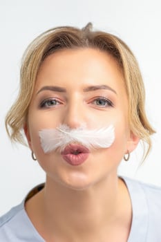 Funny beautician with a white feather-like mustache poses on white background, depilation concept. photo