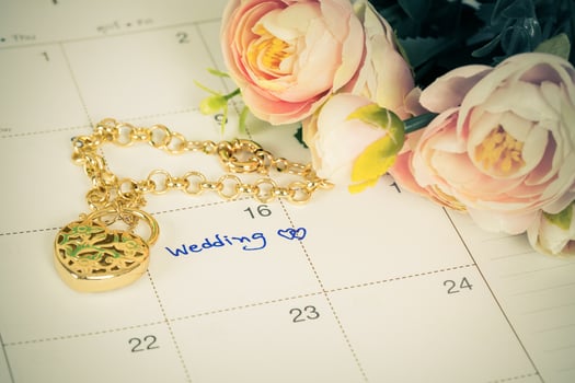 word wedding on calendar and gold bracelet with heart photo