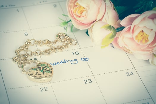 word wedding on calendar and gold bracelet with heart photo