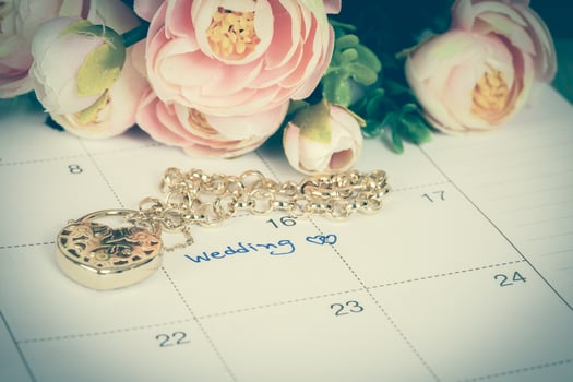 word wedding on calendar and gold bracelet with heart photo