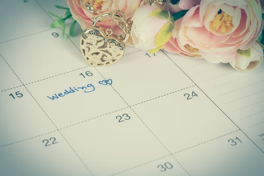 word wedding on calendar and gold bracelet with heart photo