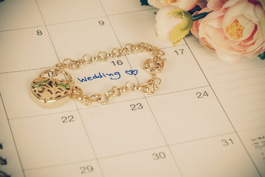 word wedding on calendar and gold bracelet with heart photo