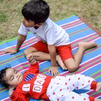 Two happy boys in society park, happy Asian brothers who are smiling happily together. Brothers play outdoors in summer, best friends. Toddler baby boy playing with his happy brother in the garden photo