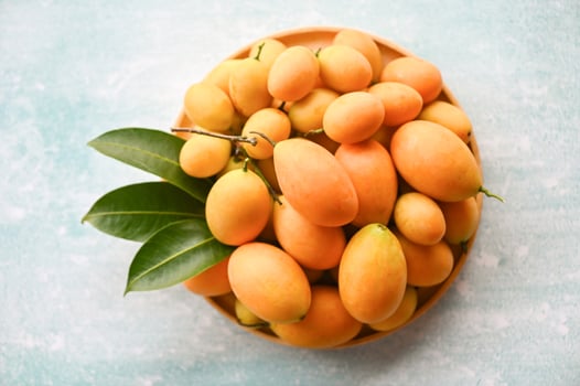 Marian plum fruit and leaves in plate on wooden background, tropical fruit Name in Thailand Sweet Yellow Marian Plum Maprang Plango or Mayong chid photo