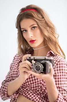 Beautiful girl with retro camera. Woman photographer in the style of the fifties photo